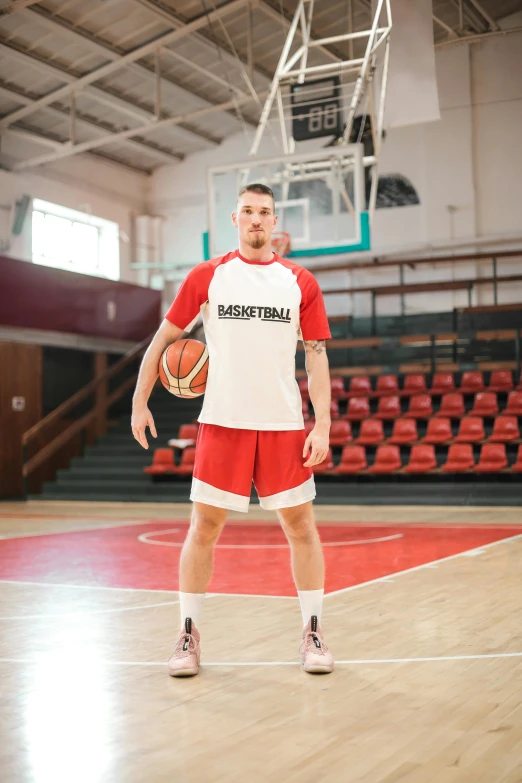 a man standing on a basketball court holding a basketball, by Paul Bird, trending on dribble, wearing a red captain's uniform, jaroslaw jasnikowski, full body image, looking confident