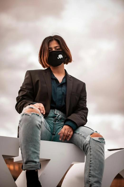 a woman wearing a face mask sitting on a bench, an album cover, trending on pexels, graffiti, wearing a black blazer, sky view, discord profile picture, cinematic outfit photo