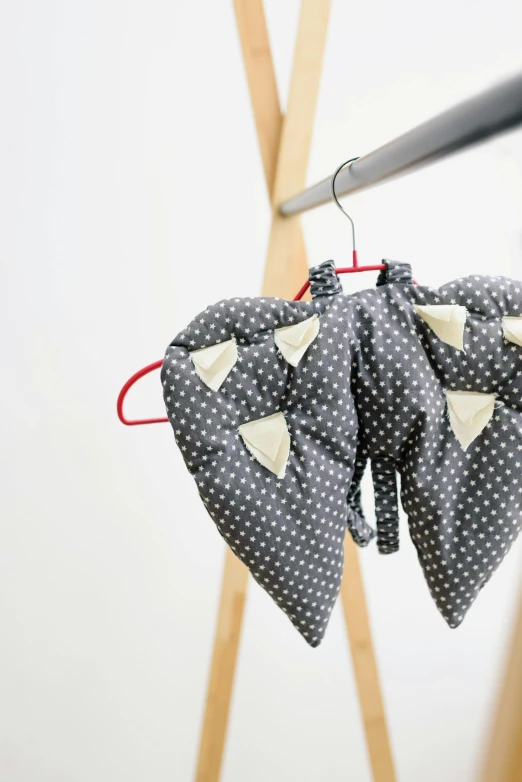 a pair of hearts hanging on a clothes rack, inspired by Louise Bourgeois, unsplash, manta ray, made of dots, dark grey, cute huge pockets hardware