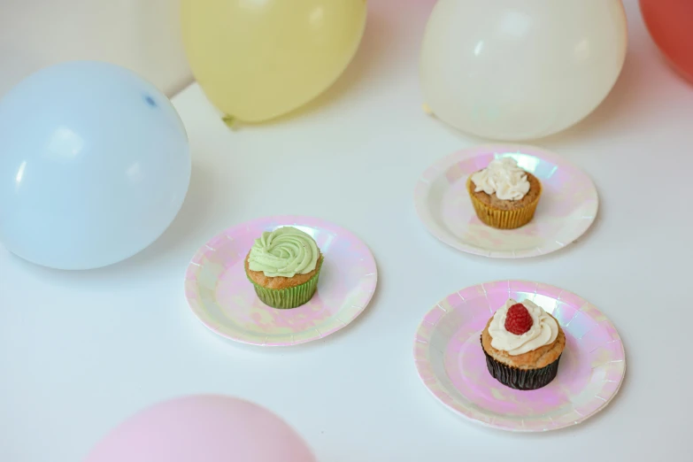 a table topped with plates of cupcakes and balloons, inspired by Peter Alexander Hay, trending on unsplash, iridescent texture, emma bridgewater and paperchase, green and pink, 3 - piece