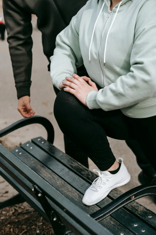 a woman sitting on top of a bench next to a man, trending on pexels, knees weak, seafoam green, streetwear, holding hands