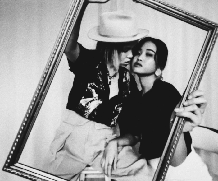 a man and a woman posing in front of a mirror, a black and white photo, tumblr, aurora aksnes and zoë kravitz, emma watson wearing fancy hat, polaroid photo style, lesbian kiss