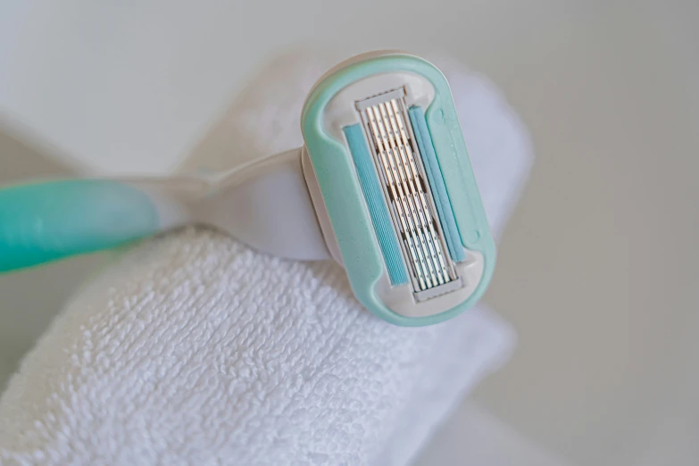 a close up of a toothbrush on a towel, white and teal garment, shaved, close-up on legs, ultra precise