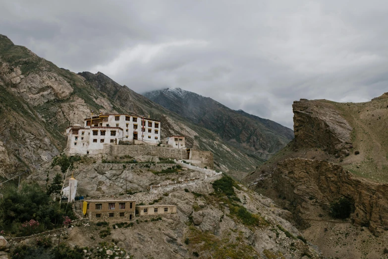 a large white building sitting on top of a mountain, inspired by Steve McCurry, pexels contest winner, villages, hindu aesthetic, brown, slight overcast weather