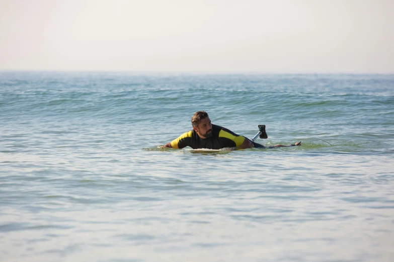 a man laying on a surfboard in the ocean, by Tom Bonson, unsplash, cornwall, bending down slightly, manuka, over his shoulder