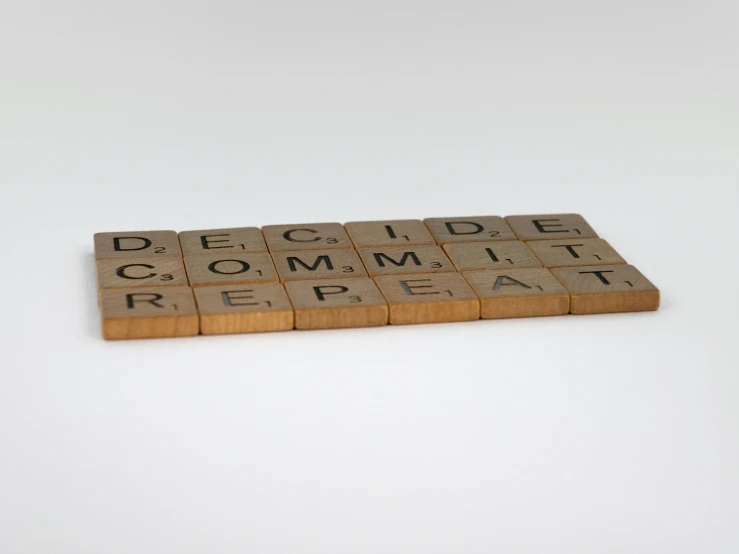 a scrabble board that says decide commit repeat, inspired by Ian Hamilton Finlay, conceptual art, wooden platforms, multi-part, tan, product shot
