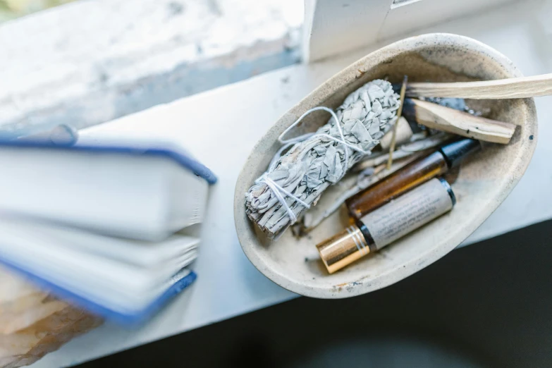 an open book sitting on top of a window sill, a still life, unsplash, process art, small vials and pouches on belt, white white and gold kintsugi, toothpaste refinery, casting a protection spell