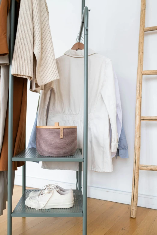 clothes hanging on a clothes rack next to a ladder, by Nina Hamnett, trending on unsplash, jar on a shelf, wearing nanotech honeycomb robe, in muted colours, bags