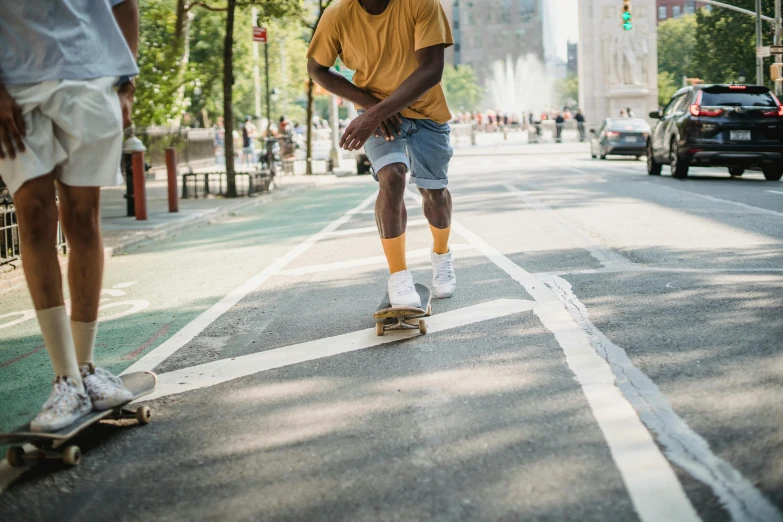 a man riding a skateboard down the middle of a street, by Carey Morris, pexels contest winner, tan skin a tee shirt and shorts, yellow clothes, jemal shabazz, new york streets