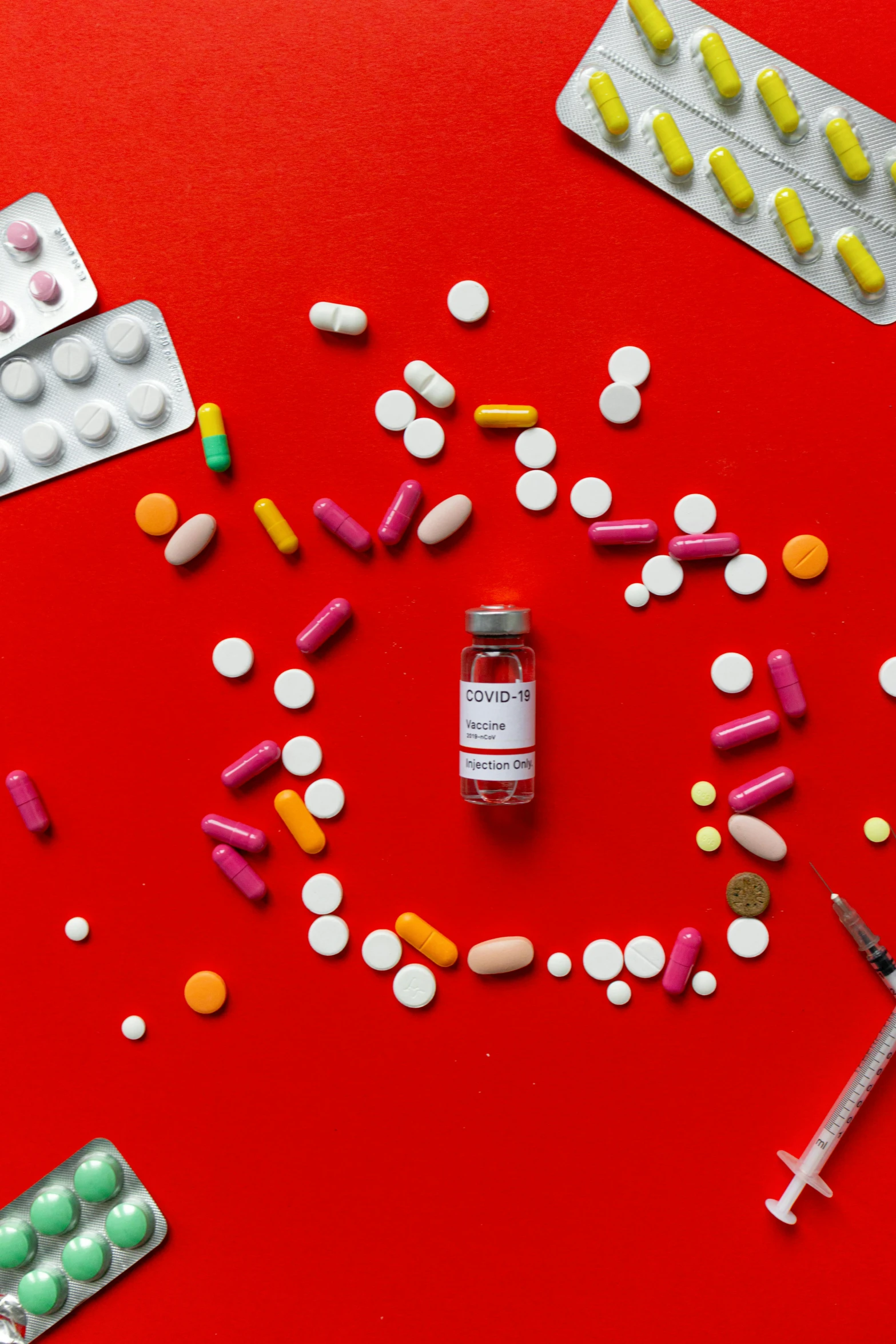 a red table topped with lots of different types of pills, inspired by Damien Hirst, pexels, antipodeans, syringe, label, product shoot, people