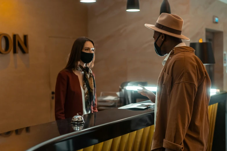 a man and a woman standing in front of a counter, by Lee Loughridge, pexels contest winner, happening, masked, caracter with brown hat, scene from live action movie, tenet