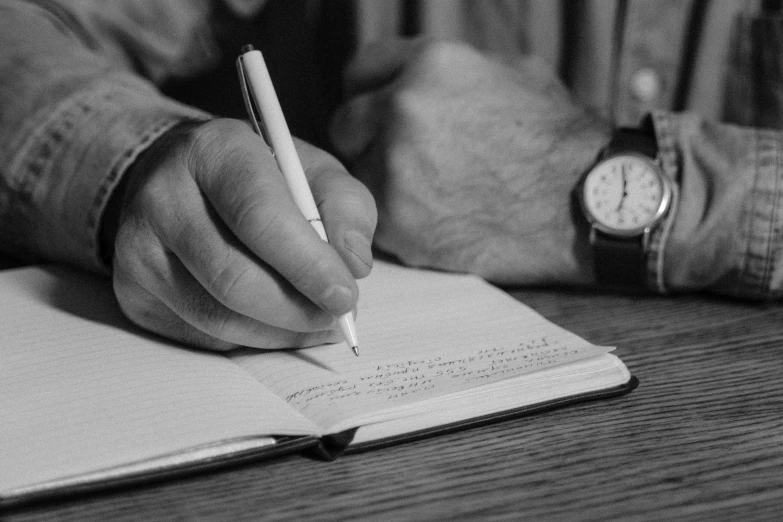 a person writing in a notebook with a pen, a black and white photo, realistic », fan favorite, tim jacobus, item