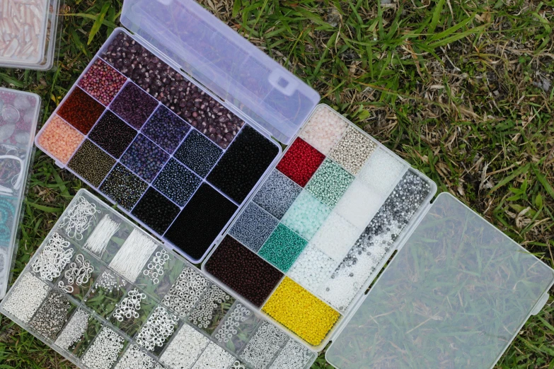 a box filled with lots of different types of beads, a pointillism painting, unsplash, kinetic pointillism, grass, grey, panels, ground - level medium shot