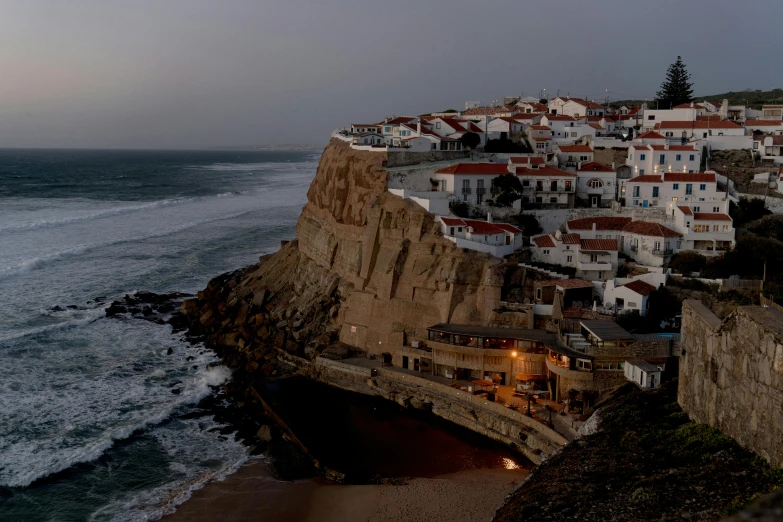 a town sitting on top of a cliff next to the ocean, by Matija Jama, pexels contest winner, farol da barra, early evening, slide show, urban surroundings