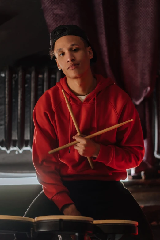 a man in a red hoodie playing drums, a portrait, trending on pexels, portrait of tom holland, ashteroth, official store photo, promotional image