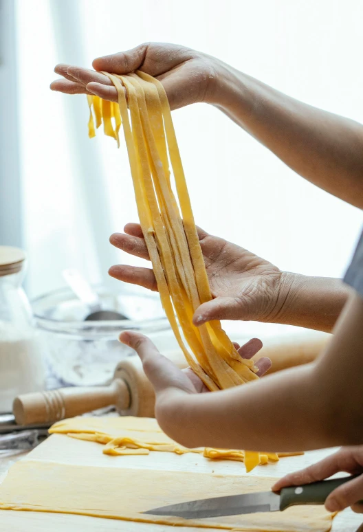 a group of people making pasta on a table, ribbon, organic, feature, square