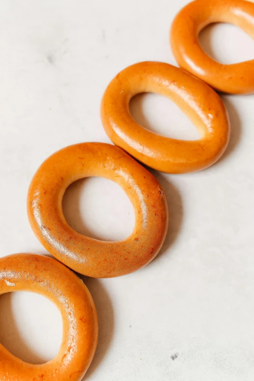 a row of glazed donuts sitting on top of a counter, by Ben Zoeller, shaped like torus ring, soft oval face, 6 pack, smooth matte