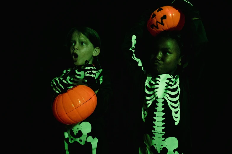 a couple of kids standing next to each other, vanitas, glow in dark, high res photograph, pumpkin, ( ( dark skin ) )