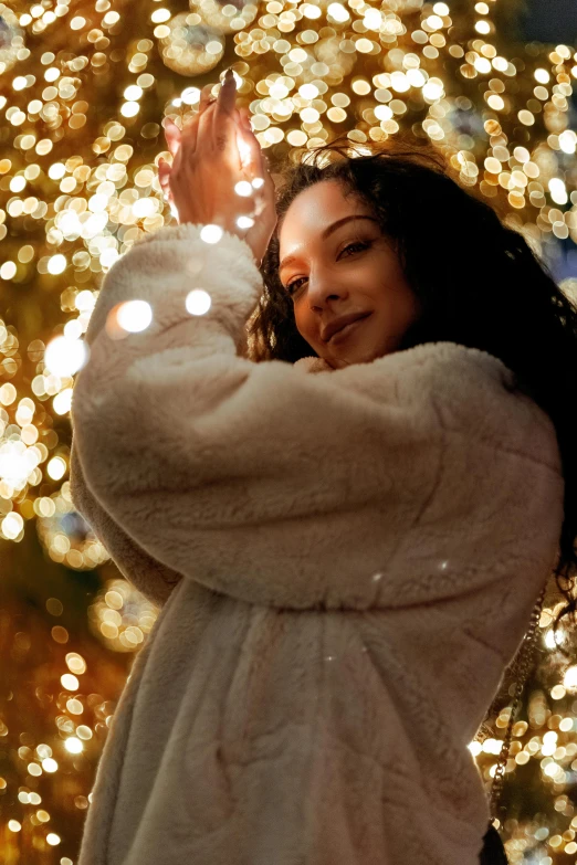 a woman standing in front of a christmas tree, trending on pexels, happening, gold and white robes, black haired girl wearing hoodie, ethereal soft and fuzzy glow, curls