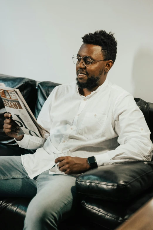 a man sitting on a couch reading a newspaper, inspired by Afewerk Tekle, pexels contest winner, hurufiyya, white dress shirt, jaylen brown, looking straight, promo image