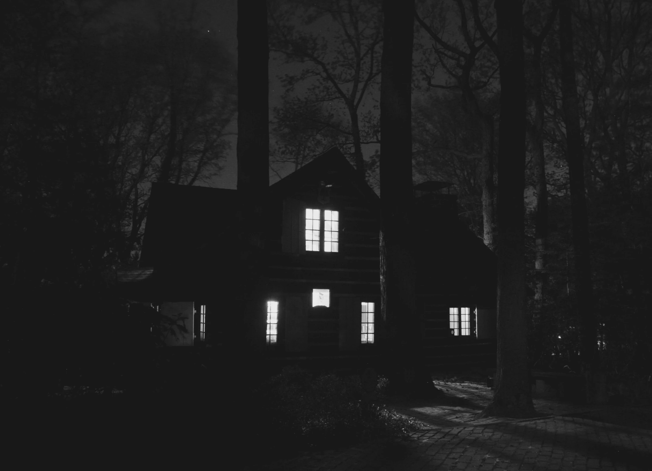 a black and white photo of a house at night, by Kristian Zahrtmann, unsplash contest winner, tonalism, witch cottage in the forest, 1940s photo, ✨🕌🌙, peaceful wooden mansion