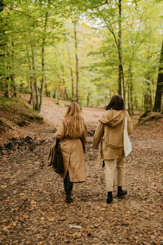 two women walking down a path in the woods, pexels contest winner, renaissance, light brown trenchcoat, caramel. rugged, friends, foliage clothing