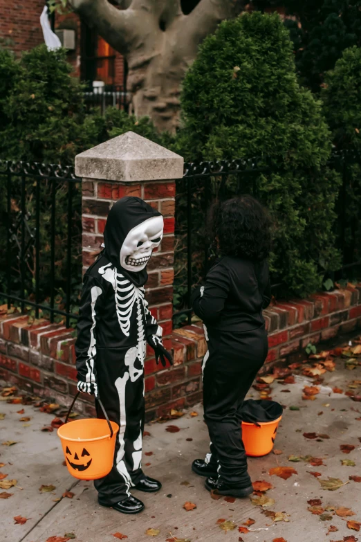 a couple of kids standing next to each other on a sidewalk, cute skeleton, profile image, diverse costumes, 2019 trending photo