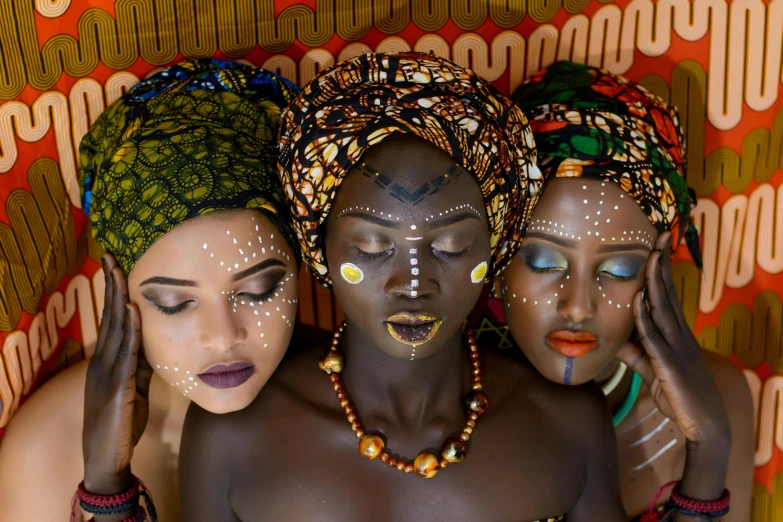 a couple of women sitting next to each other, trending on pexels, afrofuturism, facial tribal markings, three women, flatlay, wearing an african dress