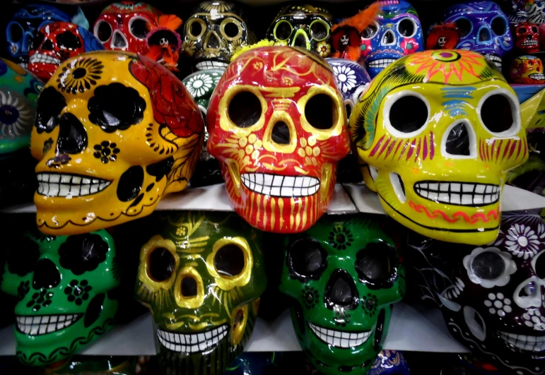 a bunch of colorful skulls sitting on top of a shelf, downtown mexico, slide show, glazed, eyes