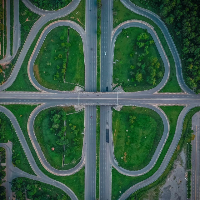 an aerial view of a road intersection in the middle of a forest, by Adam Marczyński, pexels contest winner, square lines, overpass, a green, religious