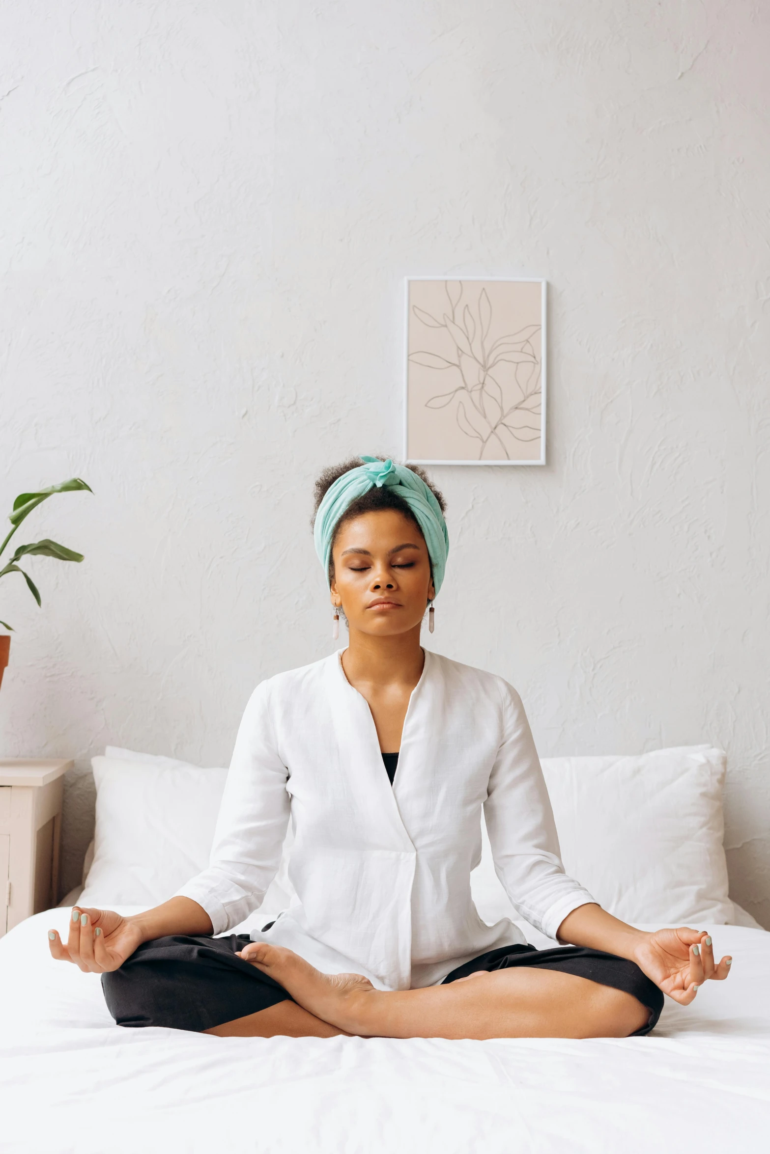 a woman sitting in a meditation position on a bed, a portrait, trending on pexels, cloth head wrap, wearing white pajamas, sitting on a couch, channeling third eye energy