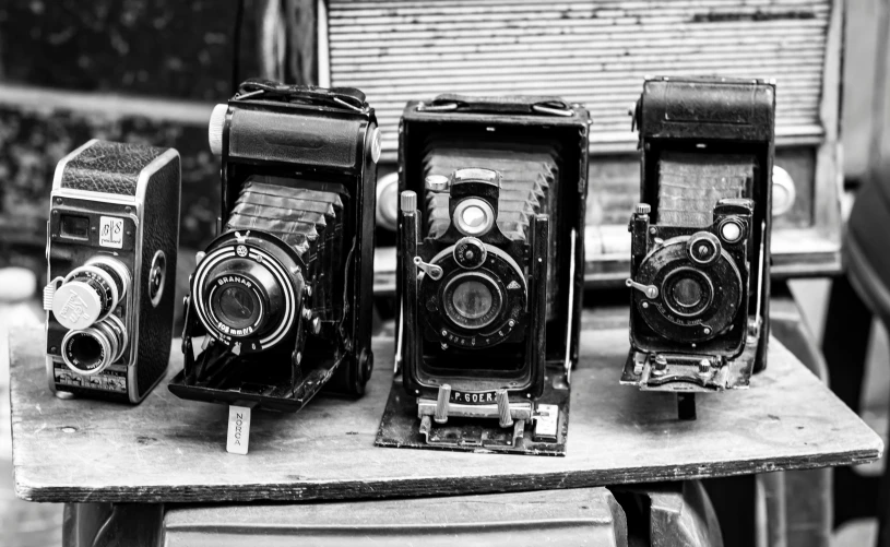 three old cameras sitting on top of a wooden table, a black and white photo, by Daniel Gelon, assemblage, photographic print, medium - format print, medium-format print, vintage - w 1 0 2 4