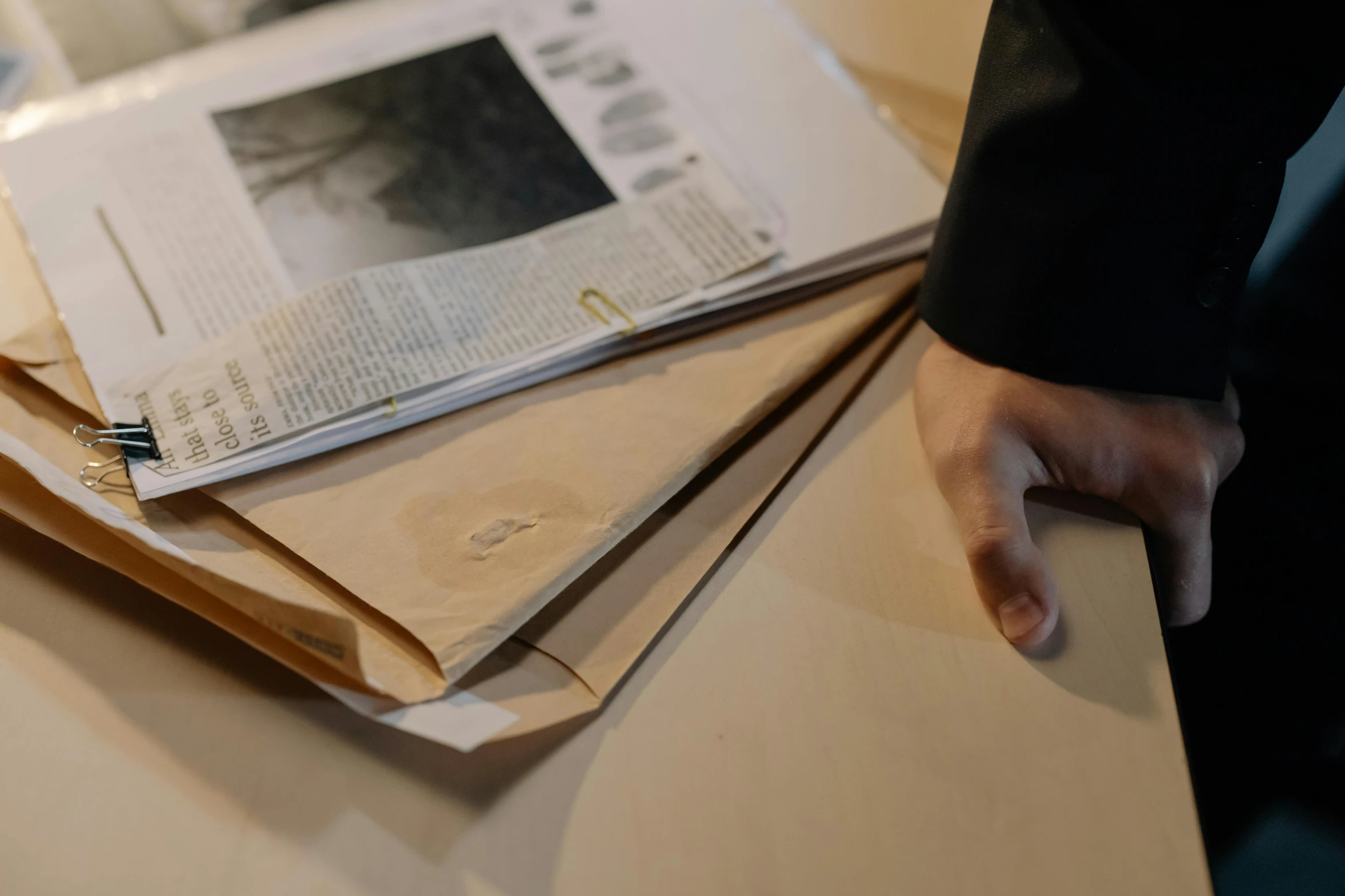 a stack of newspapers sitting on top of a table, by Sigrid Hjertén, private press, holding a wood piece, live-action archival footage, smokey burnt envelopes, inspect in inventory image