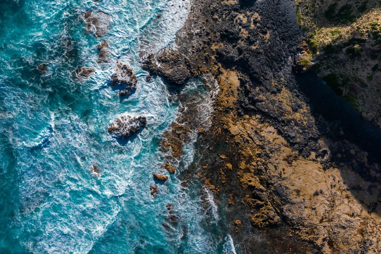 a large body of water next to a cliff, by Lee Loughridge, unsplash, process art, birdseye view, lava rock, coral reef, te pae