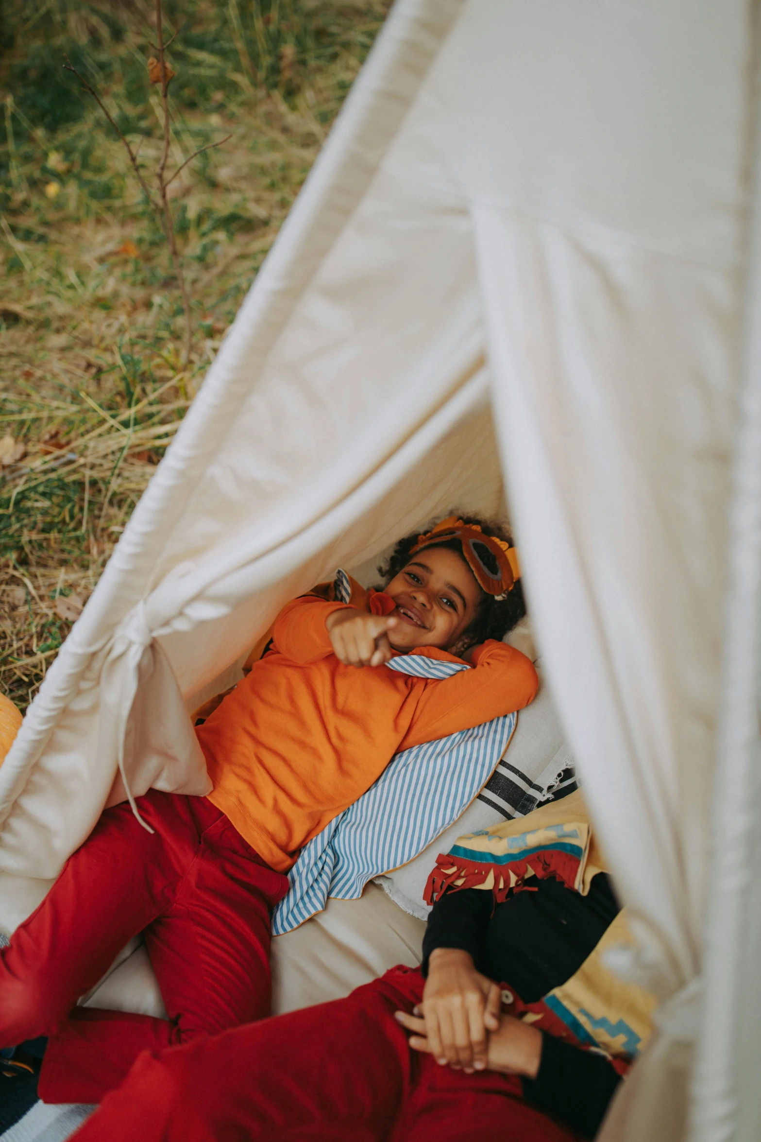 a couple of people laying in a tent, a portrait, trending on unsplash, kids playing, in the style wes anderson, outdoor photo