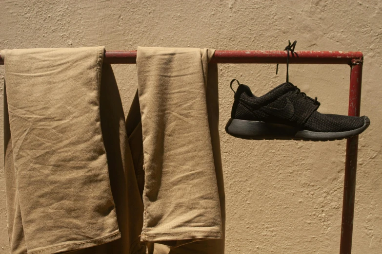 a pair of shoes hanging on a clothes rack, unsplash, photorealism, black sweatpants, caramel. rugged, hot weather, ignant
