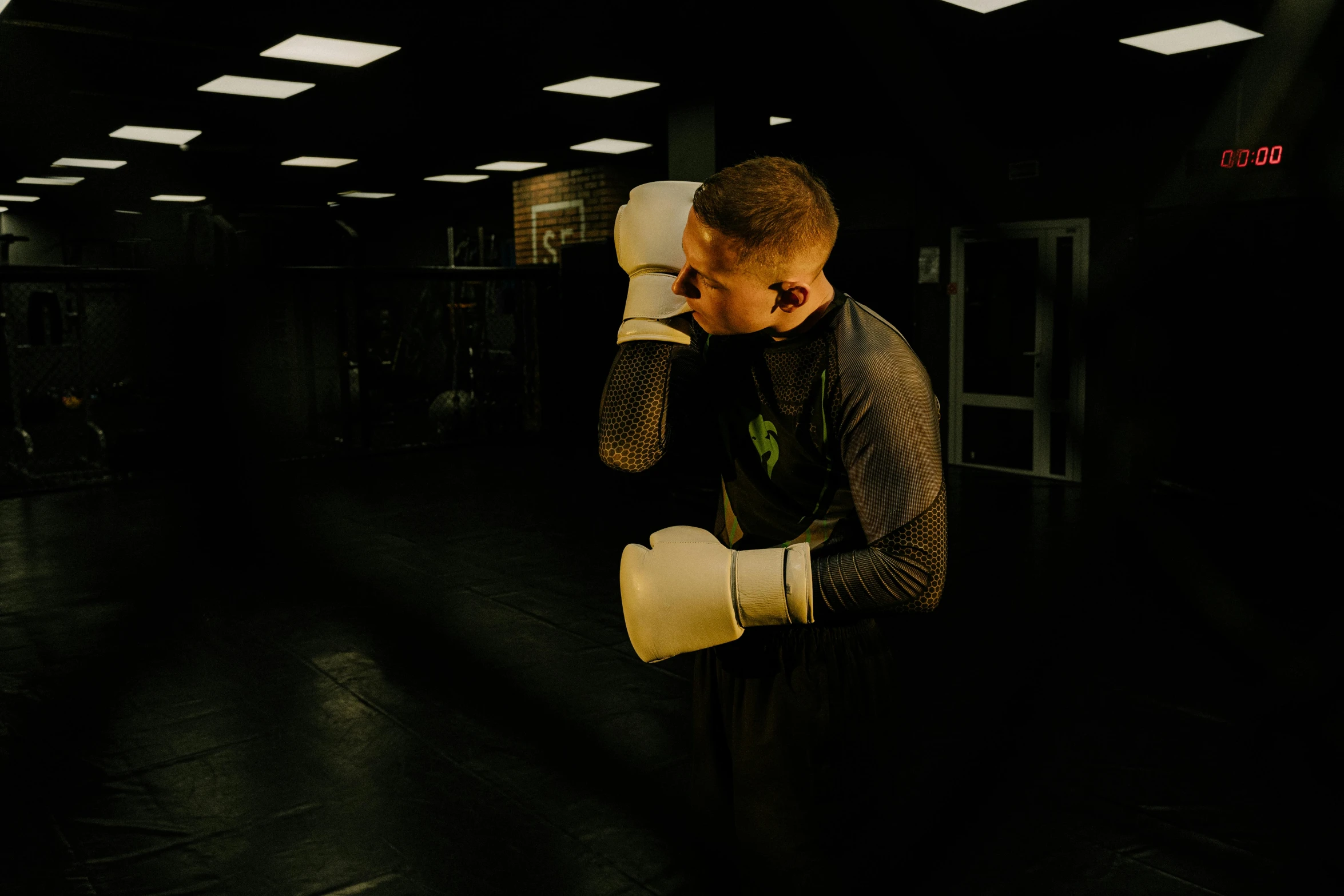 a man standing in a gym holding a pair of boxing gloves, by Emma Andijewska, happening, fighting in a dark scene, profile image