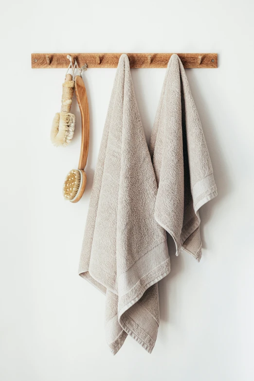 two towels hanging from a hook on a wall, inspired by Sesshū Tōyō, unsplash, renaissance, natural skin tone, promo image, taupe, made of bamboo