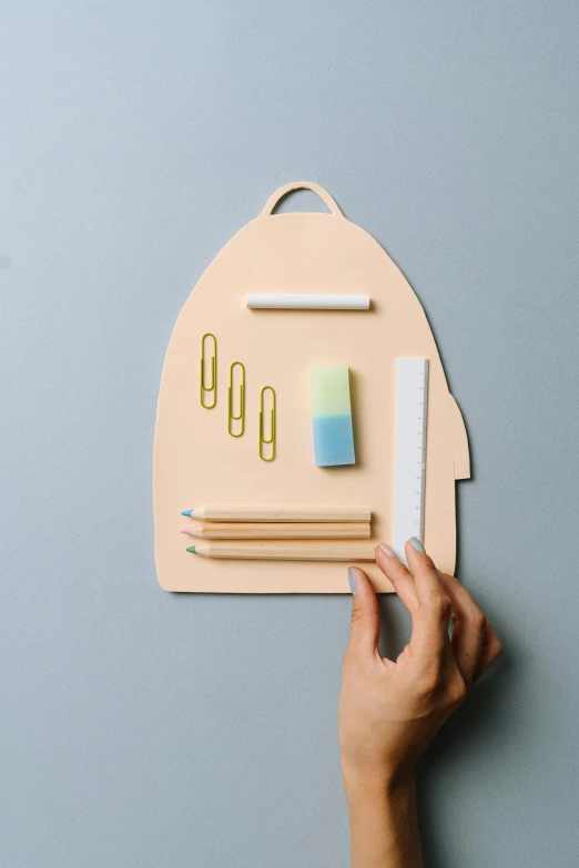 a person holding a piece of paper with writing on it, square backpack, model kit, pastel colors only, paper cutout