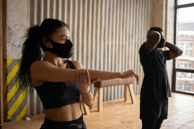 a woman in a black top and a man in a black shirt, pexels contest winner, renaissance, wearing facemask, stretching to walls, dim dingy gym, manuka