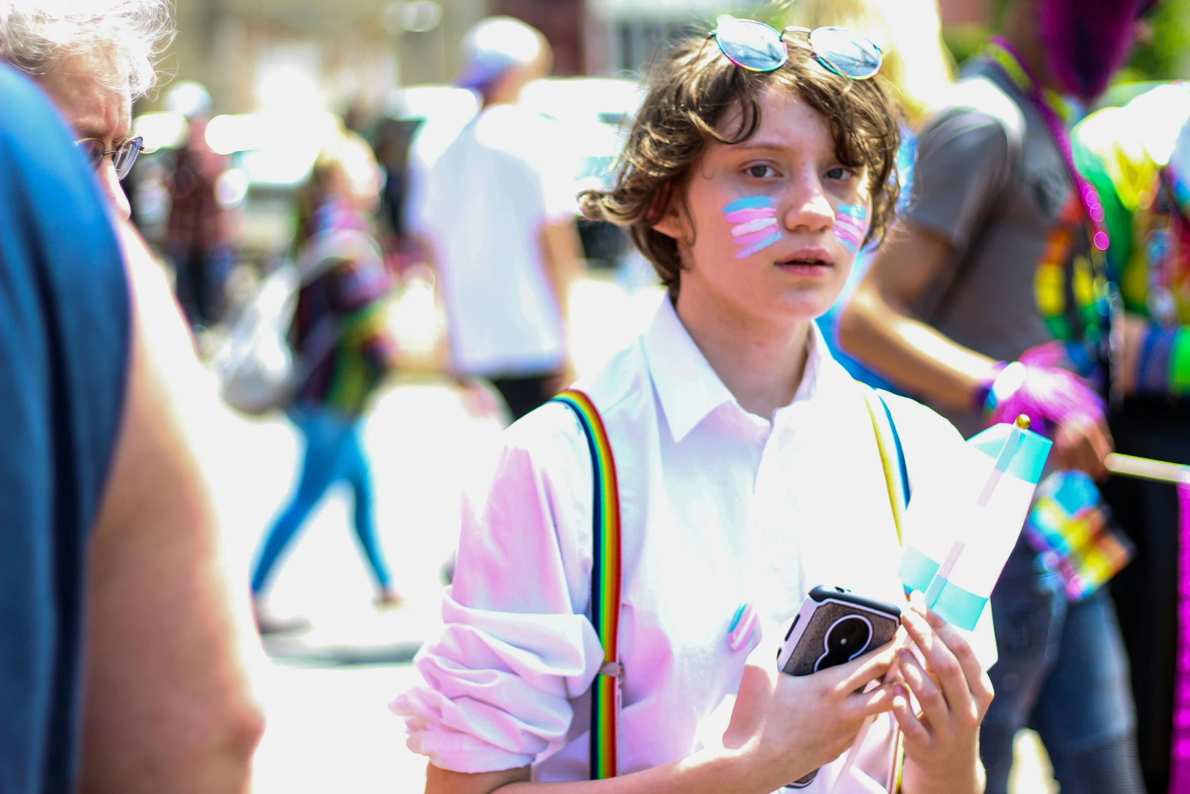 a close up of a person holding a camera, an album cover, pexels, renaissance, pride parade, cute boy, diana levin, wearing white cloths