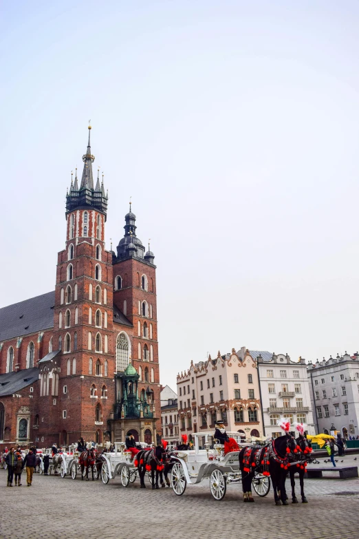 a horse drawn carriage in front of a tall building, a photo, by Adam Marczyński, pexels contest winner, baroque, alabaster gothic cathedral, poland flag, market stalls, towering above a small person