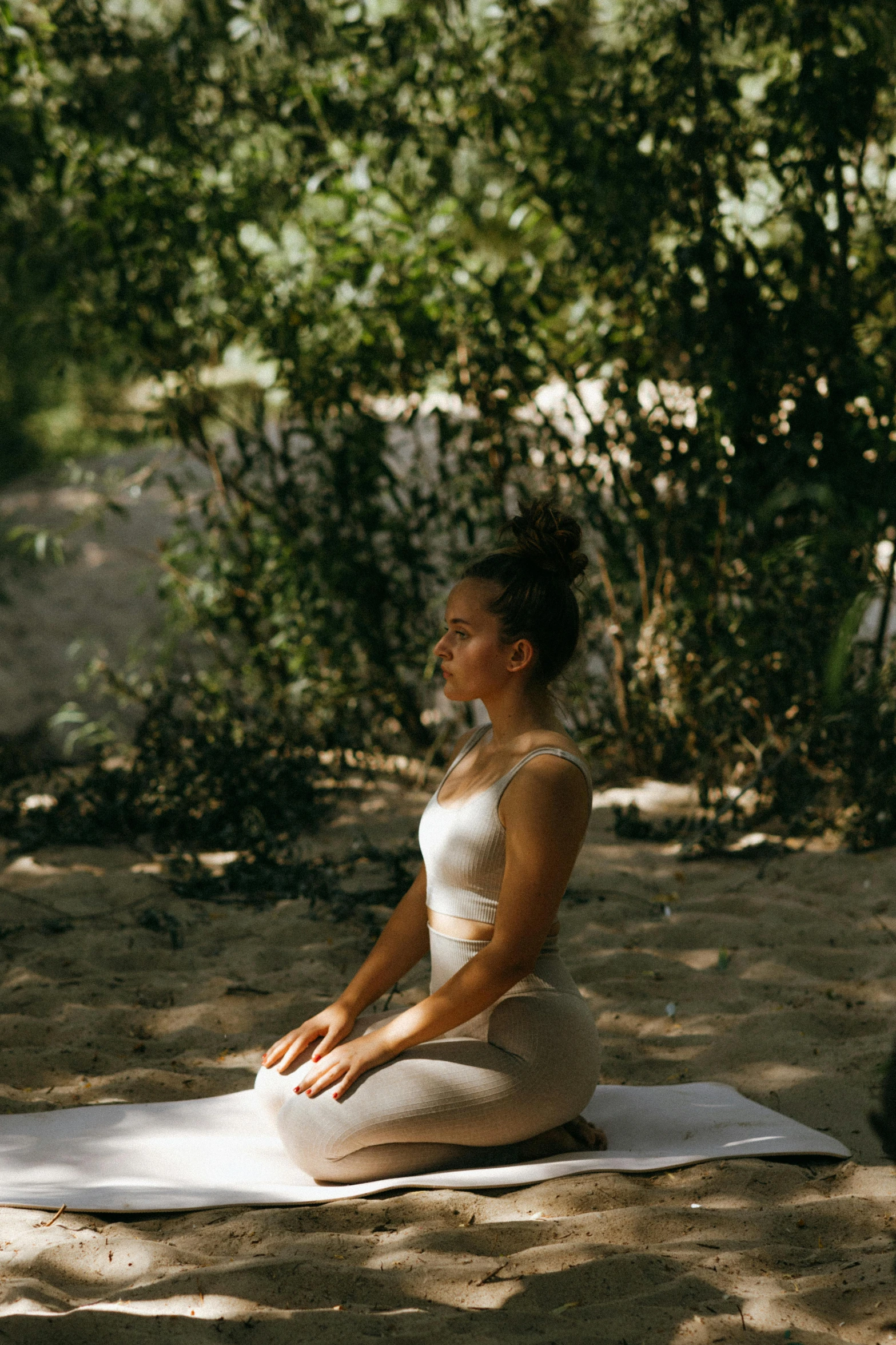 a woman sitting on a blanket in the sand, lush surroundings, yoga pose, bathed in light, cardboard