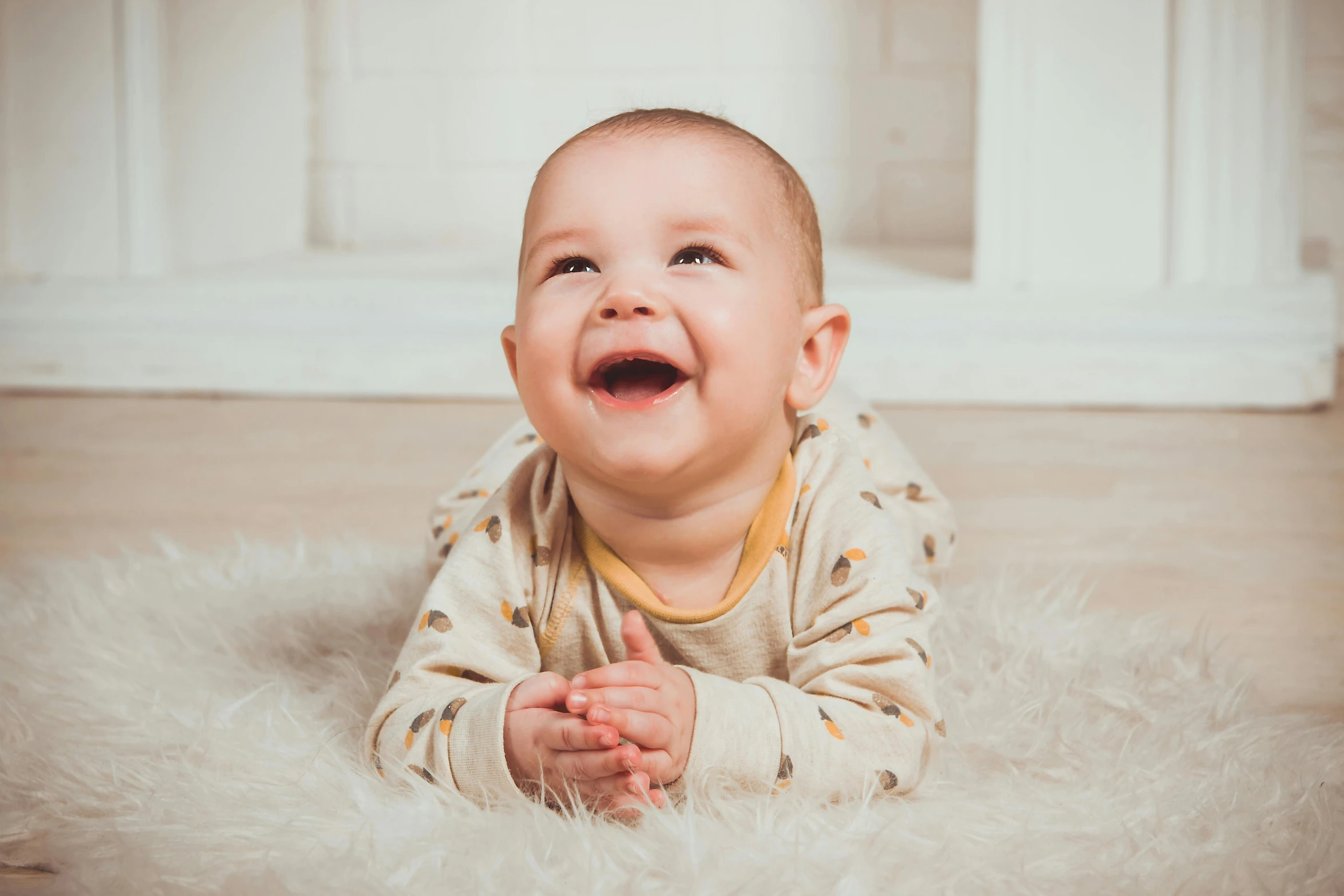 a baby laying on top of a fluffy white rug, pexels contest winner, smiling male, closeup portrait shot, looking at the ground, detailed information