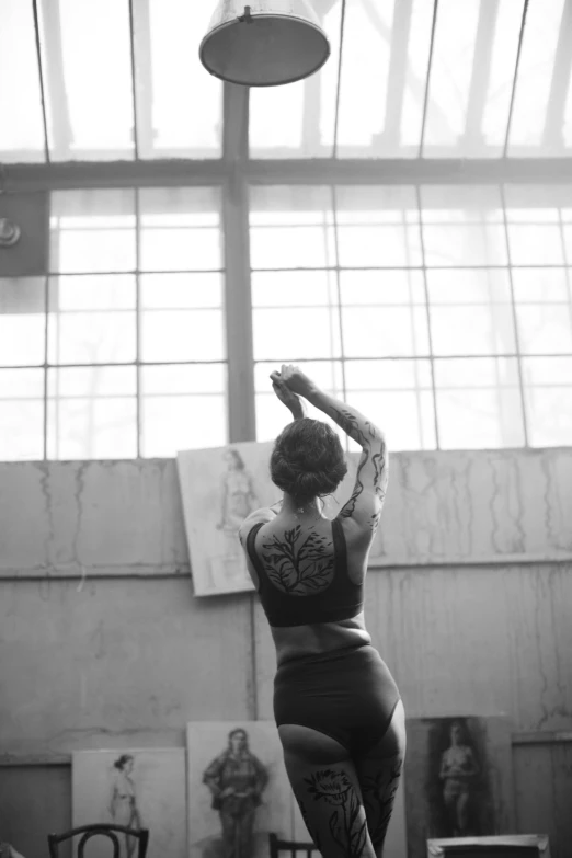 a black and white photo of a woman in a gym, inspired by Elsa Bleda, pexels contest winner, arabesque, tattooed back, modern dance aesthetic, overlooking, tattoos