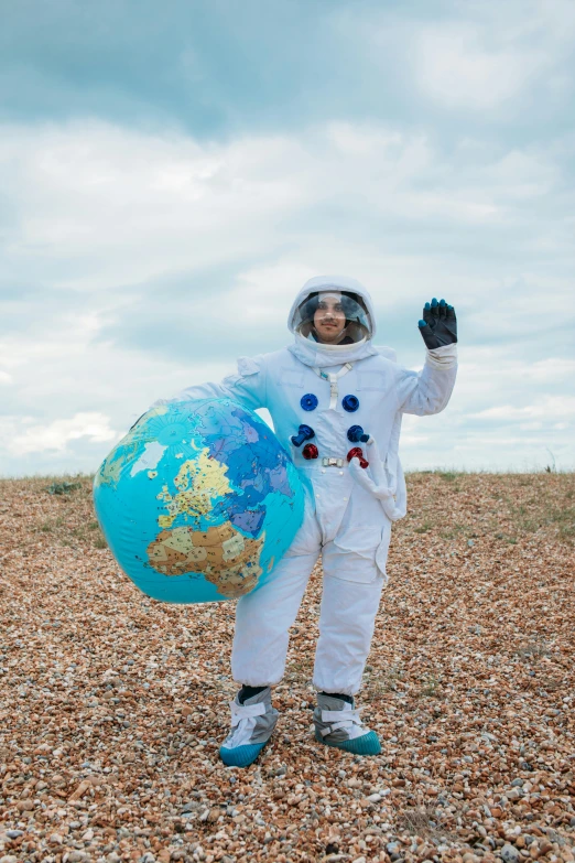 a man in an astronaut suit holding a globe, inspired by Storm Thorgerson, diverse costumes, beach on the outer rim, waving, hev suit