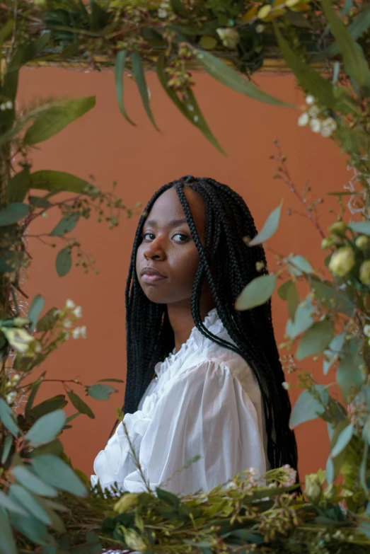 a woman standing in front of a wreath of flowers, an album cover, pexels contest winner, renaissance, maria borges, white braids, press shot, next to a plant