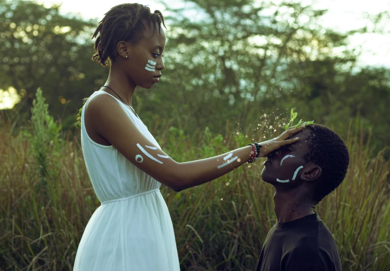 a woman standing next to a man in a field, pexels contest winner, afrofuturism, markings on her face, casting a protection spell, very kenyan, avatar image