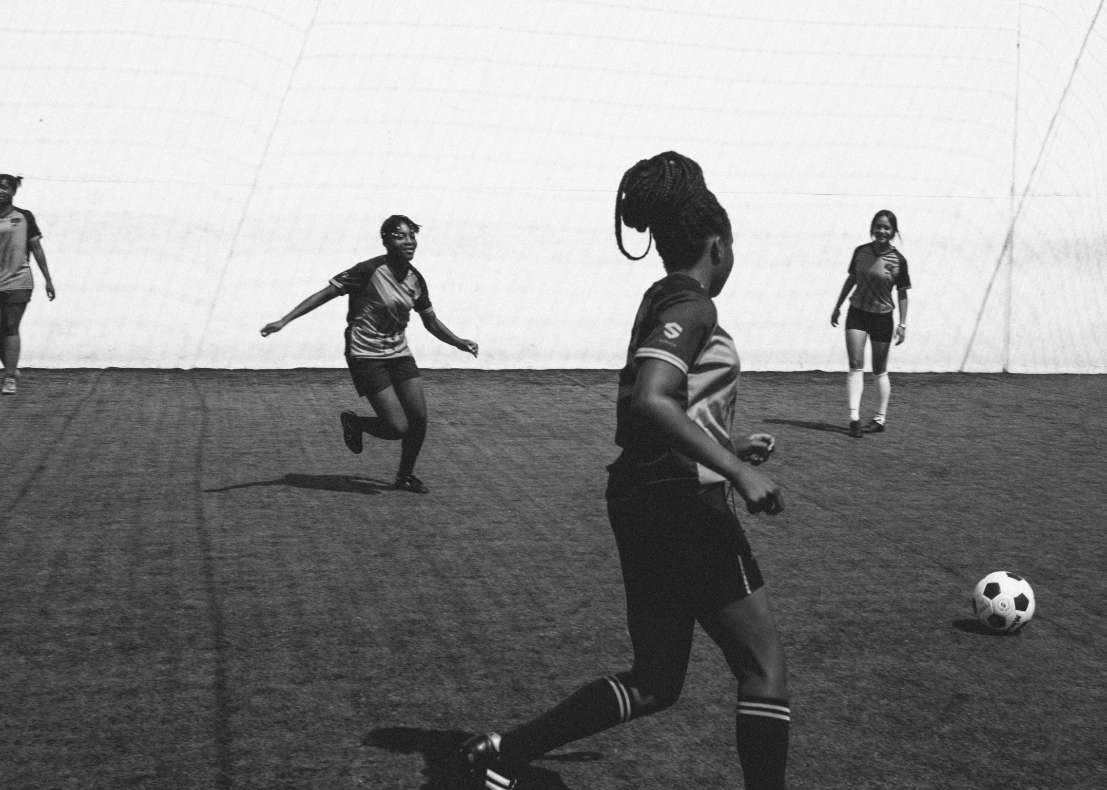 a group of young women playing a game of soccer, a black and white photo, unsplash contest winner, figuration libre, black female, low quality footage, profile image, konica minolta