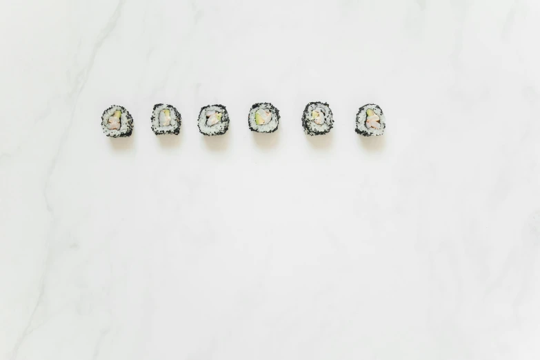 sushi rolls arranged in a row on a marble surface, an album cover, by Emma Andijewska, trending on unsplash, crystal cubism, black gems, silver，ivory, swarovski, 5 mm